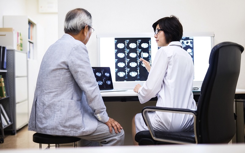 An older Asian man discusses MRI images with a female Asian doctor