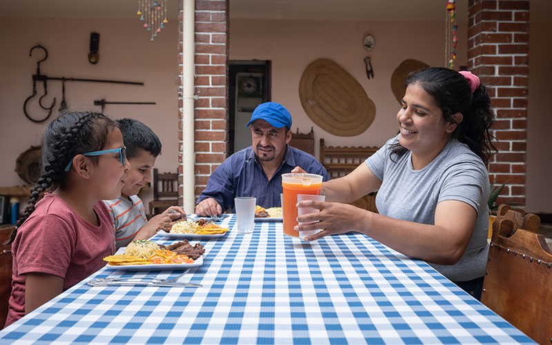 Four members of a Hispanic/Latino family seated at a dining table having a meal together